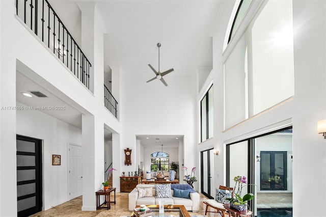 living room featuring ornamental molding, ceiling fan, and a high ceiling
