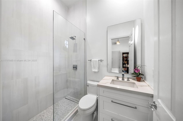 bathroom featuring toilet, a tile shower, and vanity