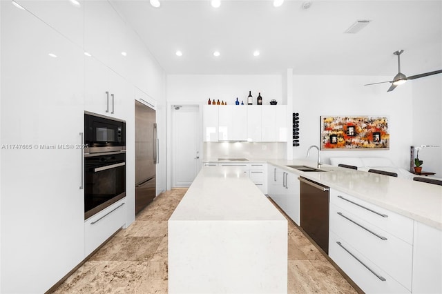 kitchen featuring built in appliances, sink, white cabinetry, a kitchen island, and ceiling fan