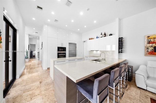 kitchen featuring white cabinets, black appliances, a breakfast bar, and kitchen peninsula
