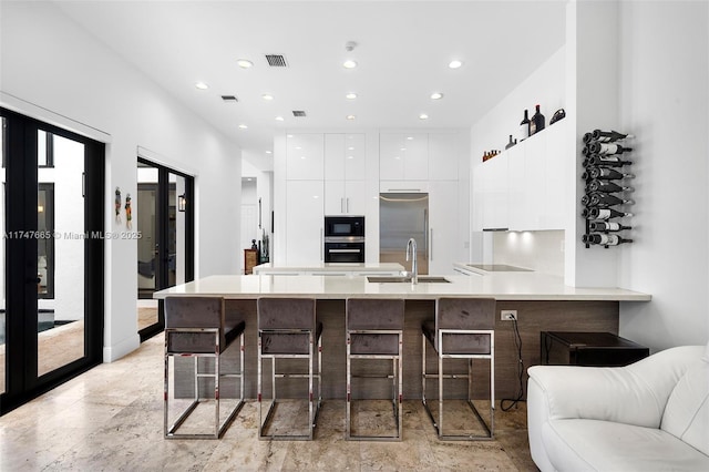 kitchen featuring a kitchen bar, sink, black appliances, kitchen peninsula, and french doors