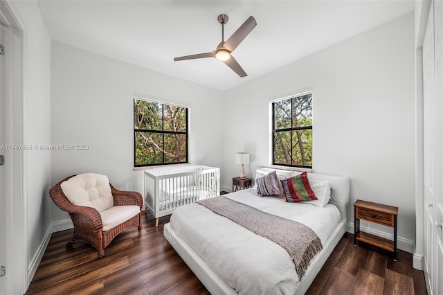 bedroom with ceiling fan, multiple windows, and dark hardwood / wood-style floors