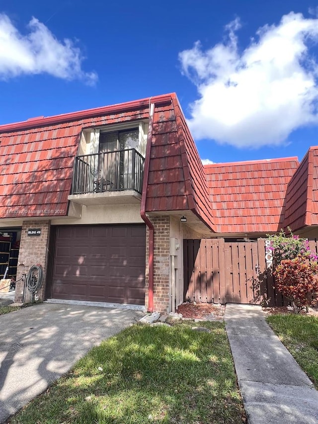 multi unit property with aphalt driveway, brick siding, a balcony, and mansard roof