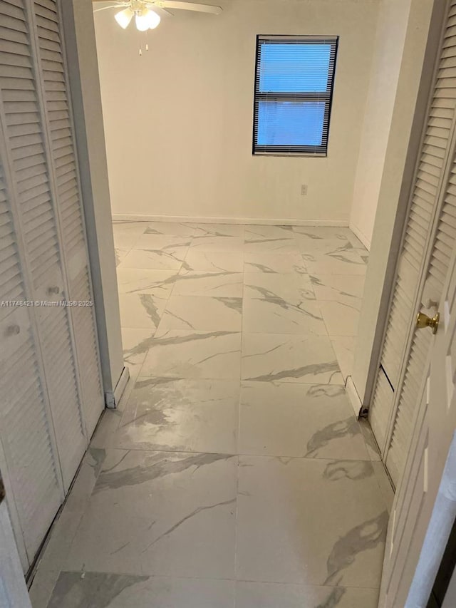 hall featuring marble finish floor and baseboards