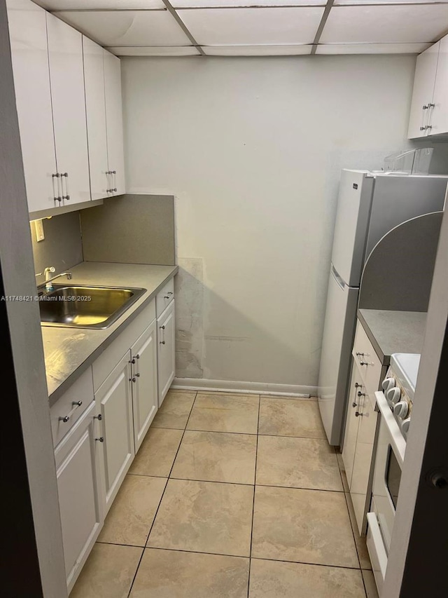 kitchen with white cabinetry, range, a drop ceiling, and a sink