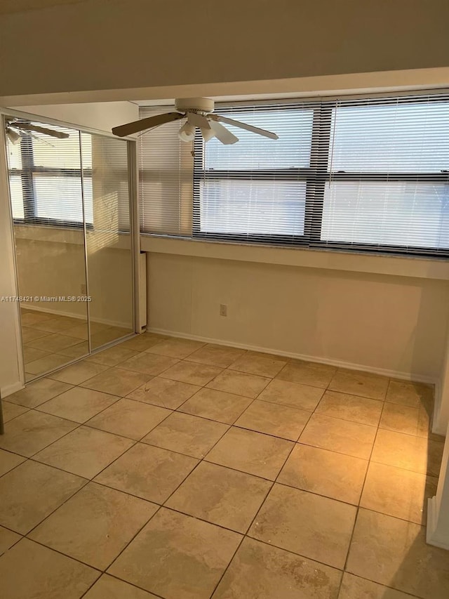 spare room featuring a ceiling fan, baseboards, and light tile patterned floors