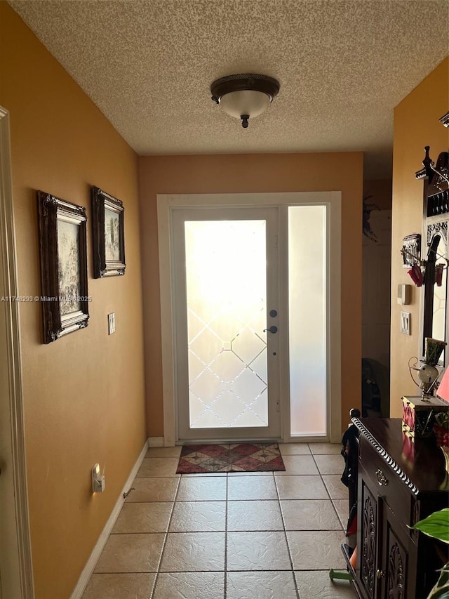 doorway with a textured ceiling, baseboards, and light tile patterned floors