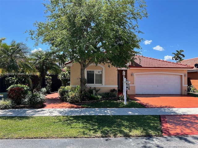 mediterranean / spanish-style home featuring a tile roof, driveway, stucco siding, and an attached garage