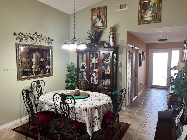 dining area with visible vents, baseboards, an inviting chandelier, vaulted ceiling, and tile patterned flooring
