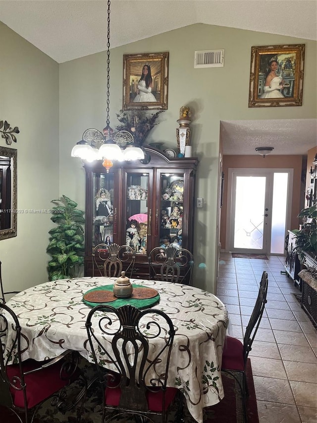 tiled dining area with visible vents and lofted ceiling