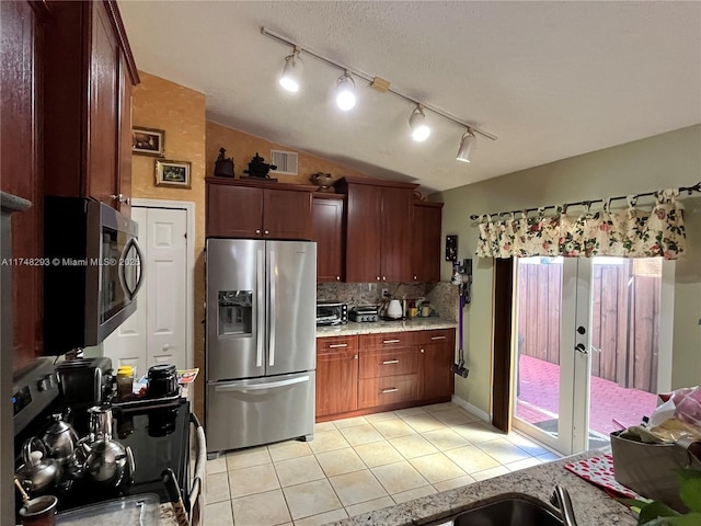 kitchen with vaulted ceiling, tasteful backsplash, appliances with stainless steel finishes, light tile patterned floors, and visible vents