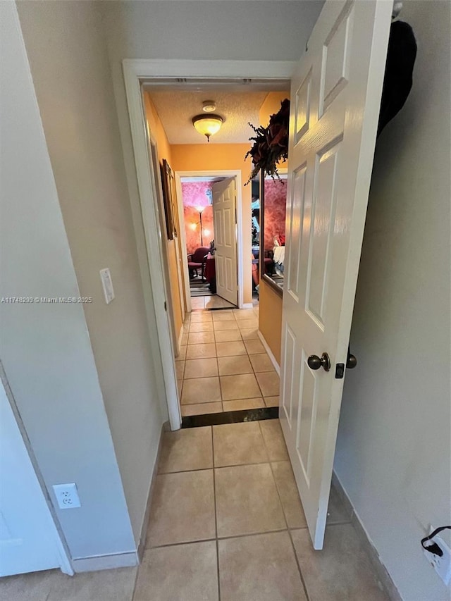 hall with light tile patterned flooring and baseboards