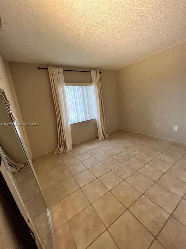 empty room with light tile patterned flooring and a textured ceiling