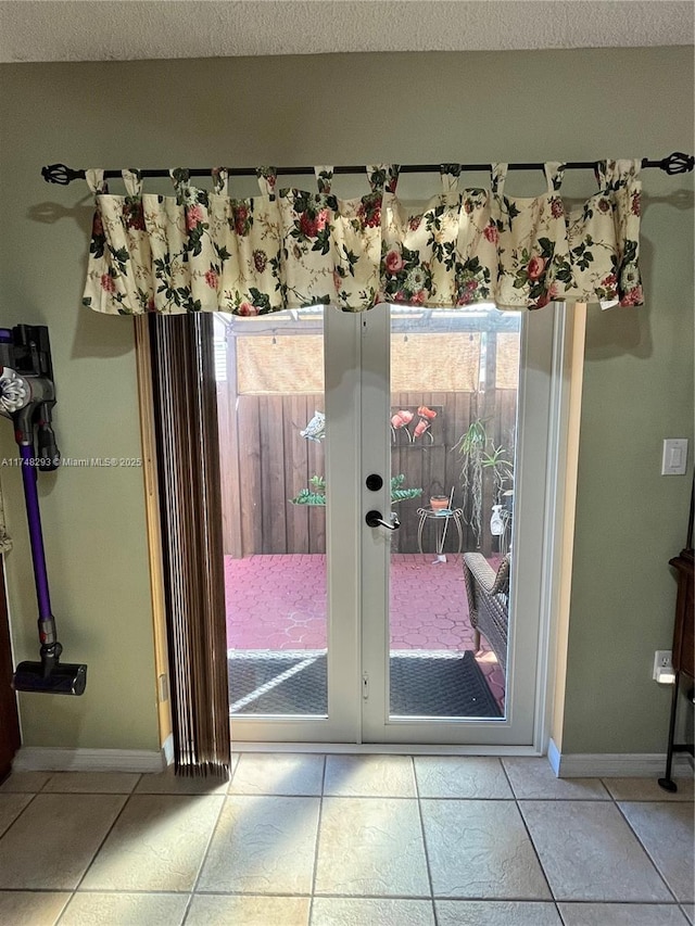 entryway featuring baseboards, a textured ceiling, and tile patterned flooring