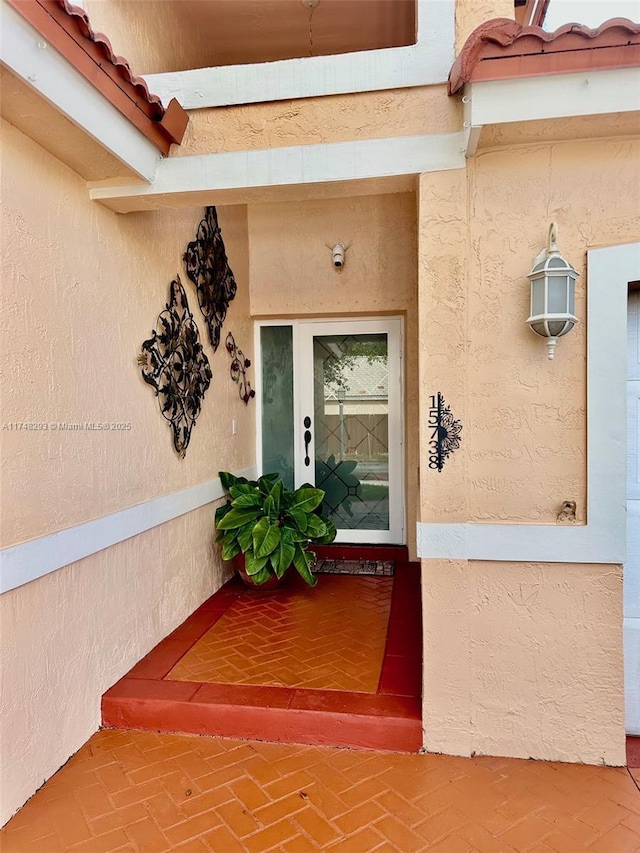 view of exterior entry featuring a tiled roof and stucco siding