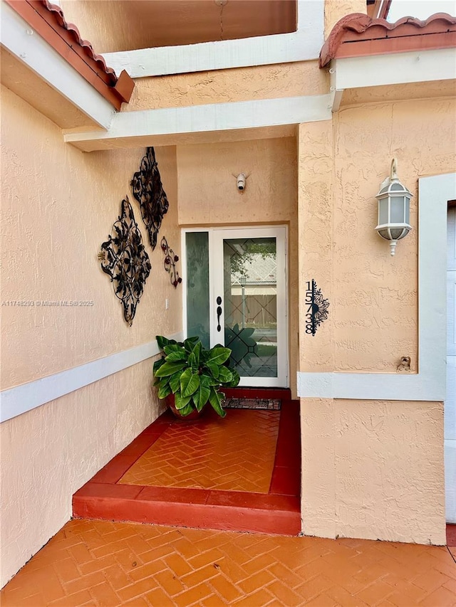 view of exterior entry featuring stucco siding and a tile roof