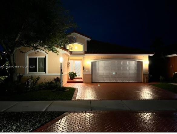 view of front of house with stucco siding, a garage, and decorative driveway