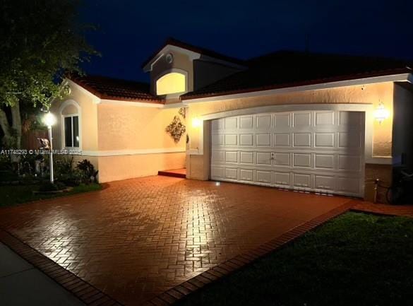 exterior space featuring a garage, decorative driveway, and stucco siding