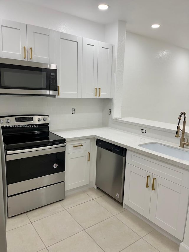 kitchen with appliances with stainless steel finishes, decorative backsplash, sink, and white cabinets