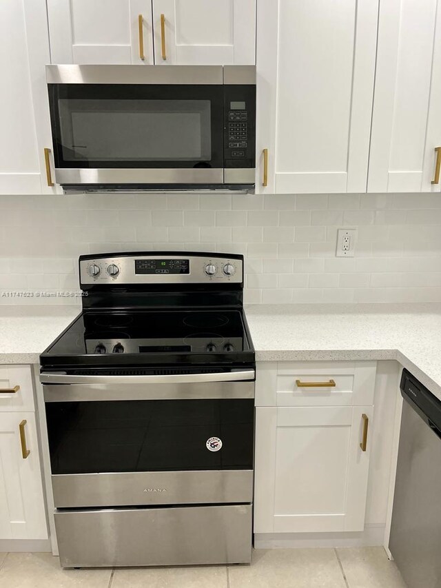 kitchen with white cabinetry, backsplash, stainless steel appliances, and light tile patterned floors