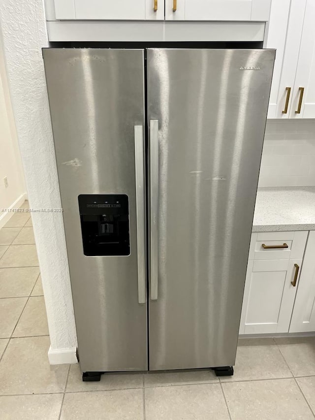 details featuring white cabinets, decorative backsplash, and stainless steel fridge with ice dispenser