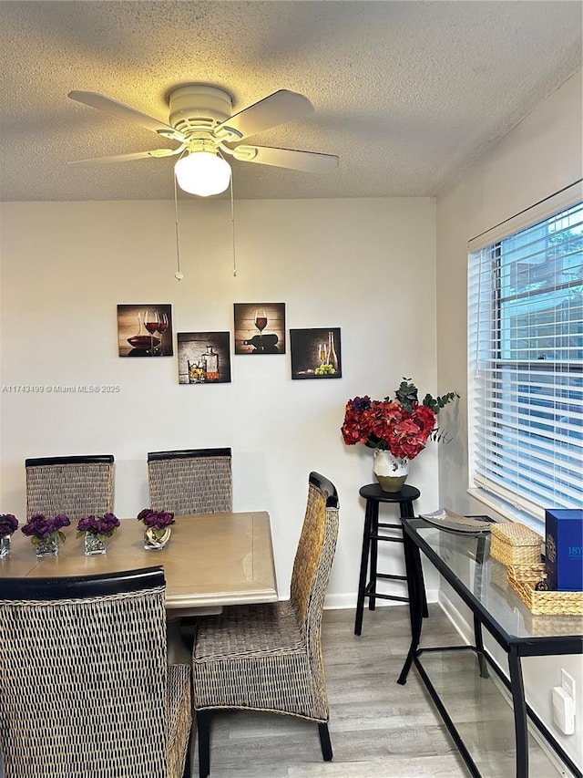 dining space with a textured ceiling, ceiling fan, and light hardwood / wood-style floors