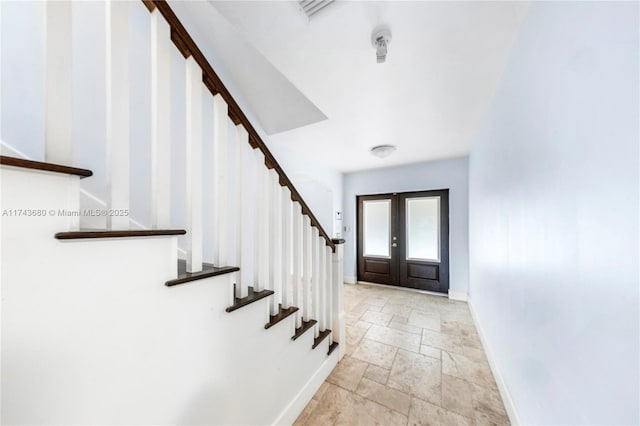 entryway with stone tile floors, stairs, baseboards, and french doors