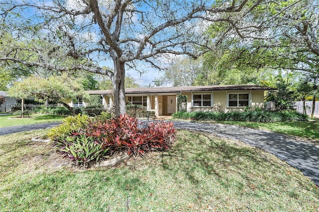 single story home with driveway, a front yard, fence, and stucco siding