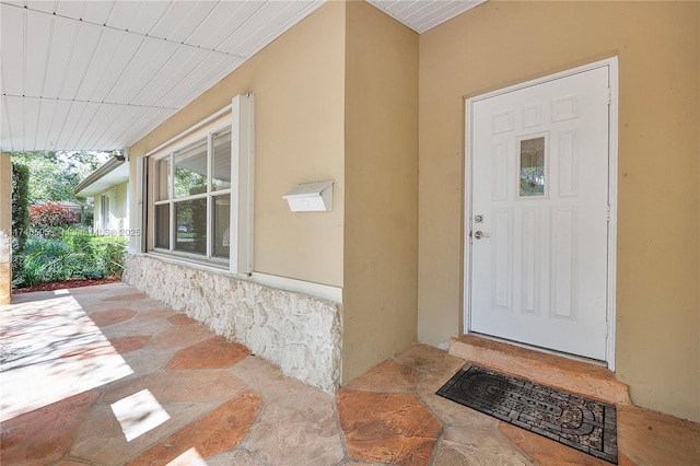 entrance to property featuring covered porch and stucco siding