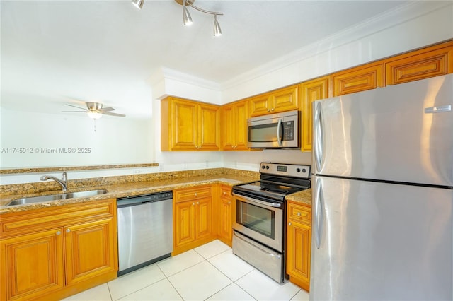 kitchen with sink, ornamental molding, light stone counters, appliances with stainless steel finishes, and light tile patterned flooring