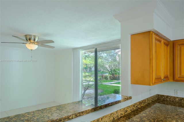 kitchen with dark stone countertops, a ceiling fan, and brown cabinets