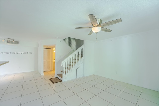 spare room featuring visible vents, a ceiling fan, tile patterned flooring, and stairs