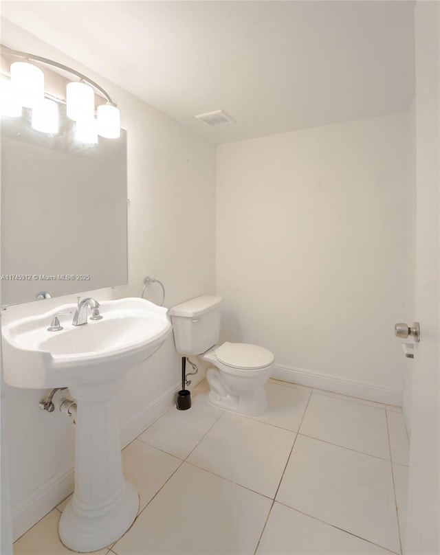 half bathroom with toilet, baseboards, tile patterned flooring, and visible vents