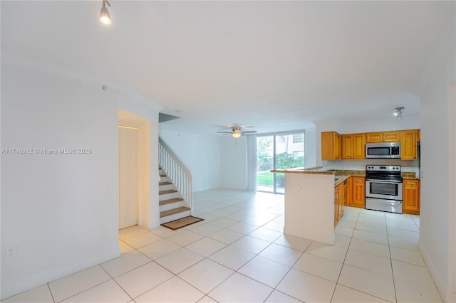 kitchen featuring ceiling fan, light tile patterned flooring, stainless steel appliances, and kitchen peninsula