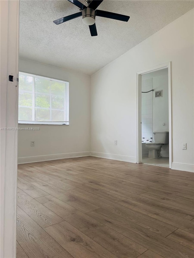 empty room featuring wood-type flooring, ceiling fan, baseboards, and a textured ceiling