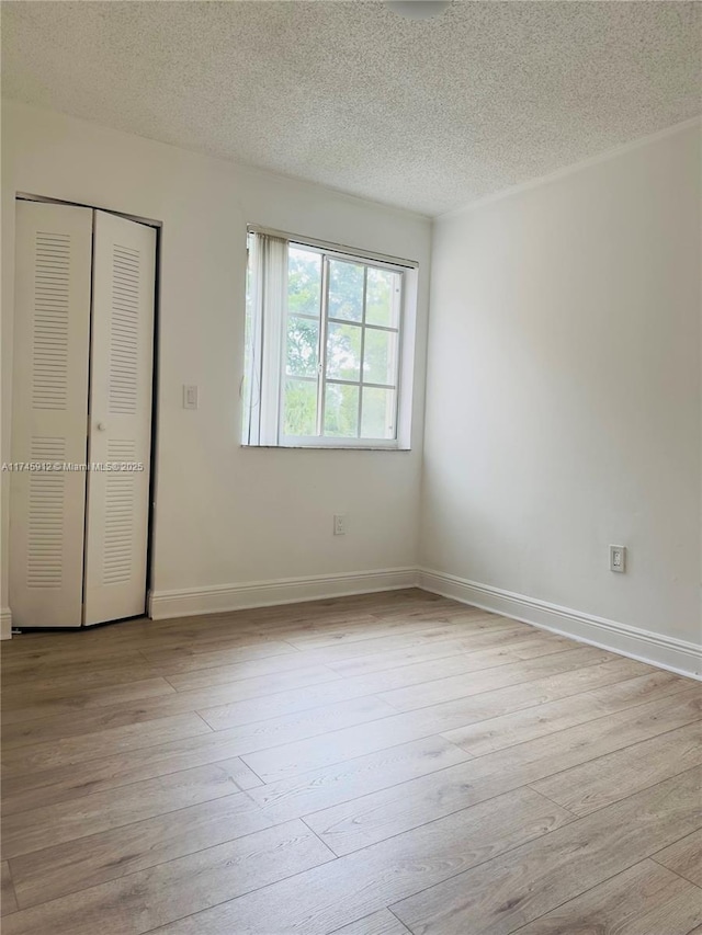 unfurnished bedroom featuring light wood-type flooring, a textured ceiling, and a closet