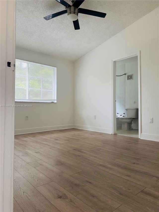 unfurnished room with hardwood / wood-style floors, vaulted ceiling, ceiling fan, and a textured ceiling