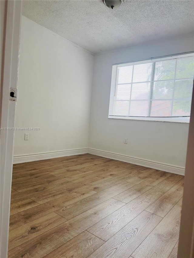 unfurnished room with light hardwood / wood-style floors and a textured ceiling