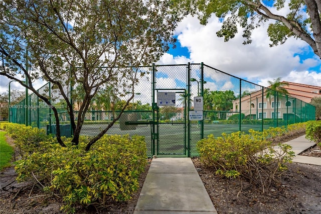 view of tennis court with fence and a gate