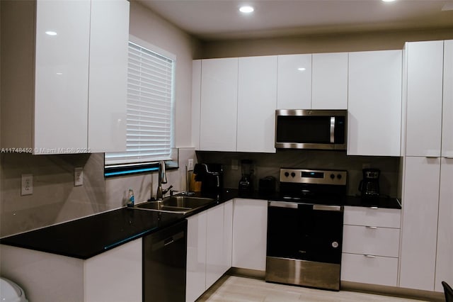 kitchen featuring appliances with stainless steel finishes, sink, white cabinetry, and backsplash