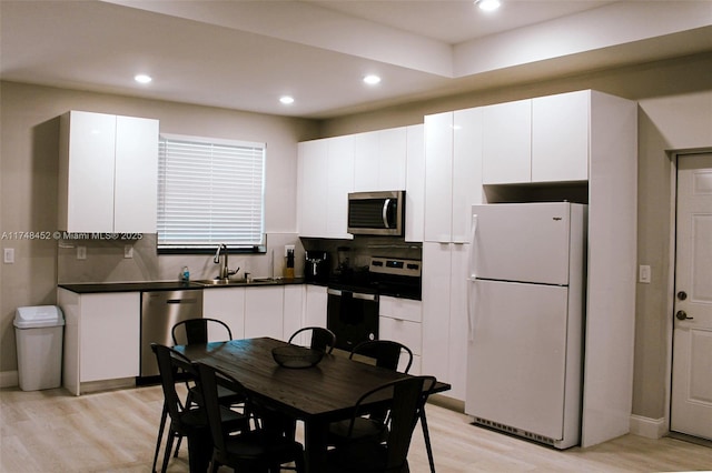 kitchen with sink, stainless steel appliances, white cabinets, and light hardwood / wood-style floors