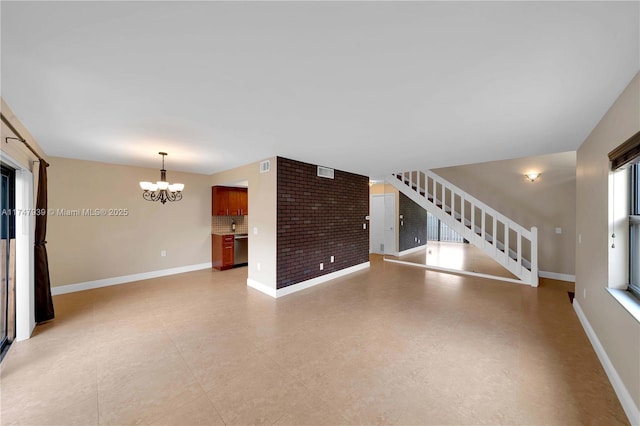 unfurnished living room featuring brick wall and a chandelier