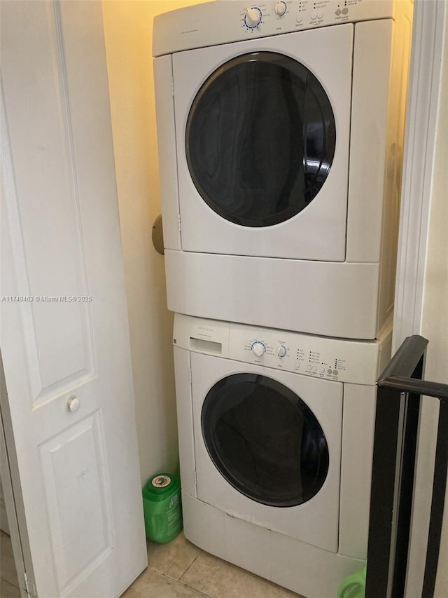 clothes washing area featuring stacked washing maching and dryer and light tile patterned flooring