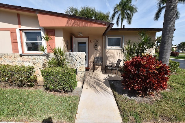 view of exterior entry with stone siding and stucco siding