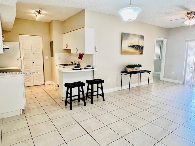 kitchen with white fridge, sink, white cabinetry, a textured ceiling, and kitchen peninsula