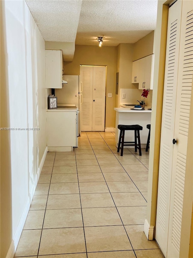 kitchen featuring a textured ceiling, white cabinetry, and light tile patterned floors