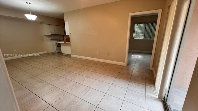 spare room featuring baseboards, a textured ceiling, and light tile patterned floors