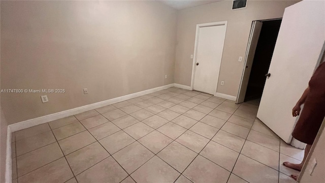 empty room featuring baseboards, visible vents, and light tile patterned floors