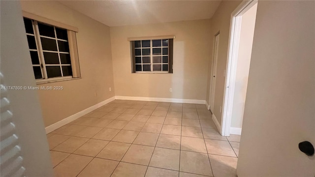 empty room with light tile patterned flooring and baseboards