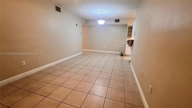 tiled empty room featuring a textured ceiling